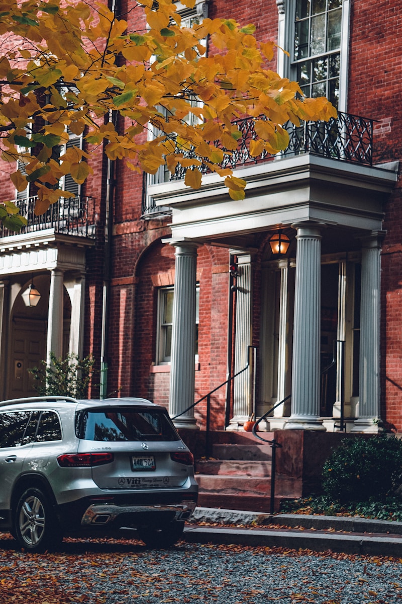 home and auto, a car parked in front of a brick building with a tree in the front