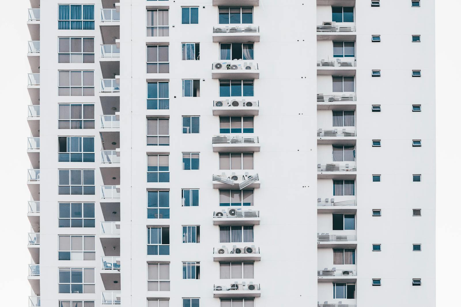 A sleek, modern high-rise building with a glass facade and multiple balconies, showcasing urban architecture, condo